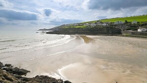A coastal beach with a clear sky, waves, and houses on a green hill. - Blue Crab by Interhome (Mevagissey)