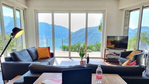 Un salon moderne doté d’une grande fenêtre donnant sur un paysage montagneux.