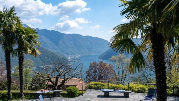 Un espace piscine doté de chaises longues et offrant une vue sur les montagnes et un lac.