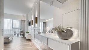 Moderni hotellihuone, jossa on suuri sänky, työpöytä ja oleskelualue.