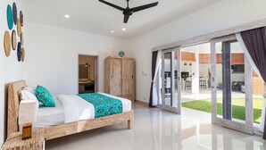 A spacious bedroom with a large bed, a wooden wardrobe, and a view of the outdoor area. - Luxurious 4BR Villa With Pool, Bali Villa 2206 (Seminyak)