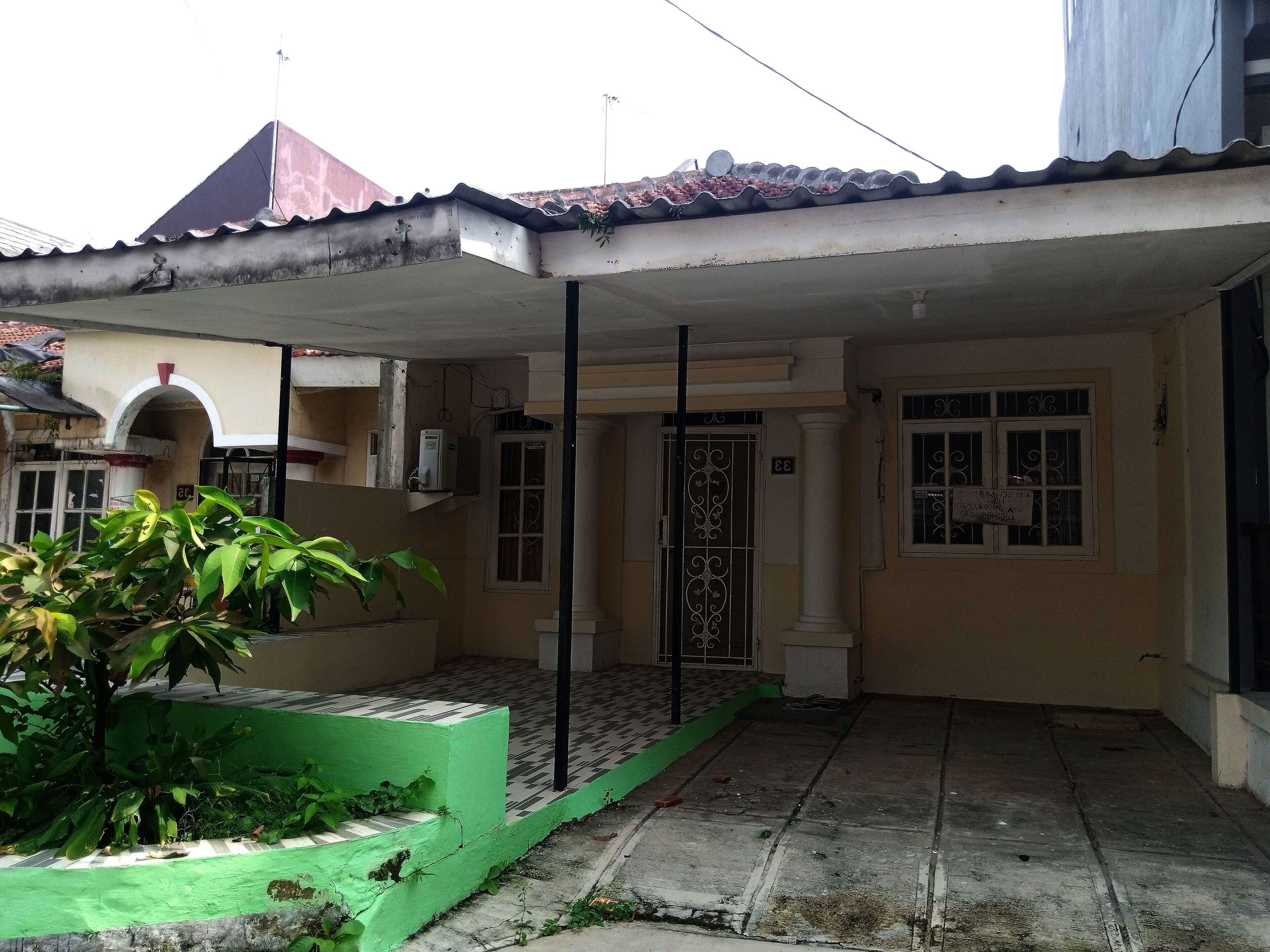 A residential building with a covered patio, a gated entrance, and a small garden area.