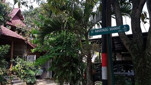 A street sign with a traditional roof structure and lush greenery in the background. - Hotel O Pahlawan Udyana Syariah (Sentul City)
