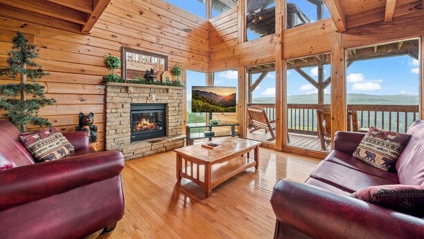 L’intérieur d’un chalet en bois est doté d’une cheminée, de canapés en cuir et d’un balcon offrant une vue panoramique.