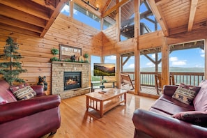 A wooden cabin interior with a fireplace, leather sofas, and a balcony with a scenic view. - Breathtaking Views, perfect location, Free ticket to Dollywood and other attractions! (Sevierville)