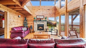 L’intérieur d’un chalet en bois est doté d’une cheminée, de canapés en cuir et d’un balcon offrant une vue panoramique.