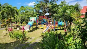 Un'area giochi con scivoli e strutture per arrampicata, immersa nel verde.