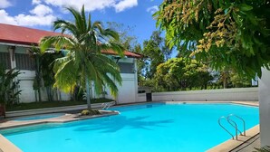 Piscina con acqua cristallina e trasparente, circondata da palme e vegetazione.