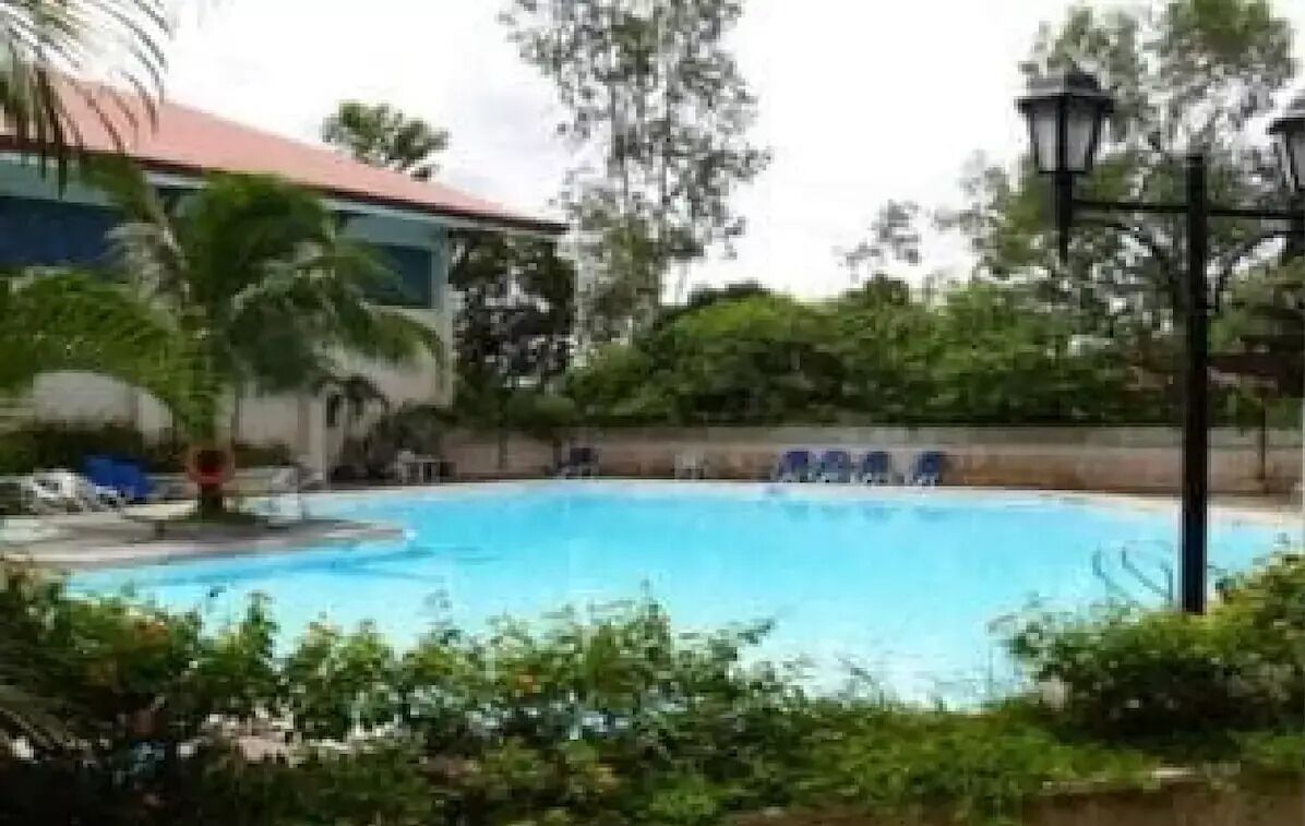 Una piscina rodeada de vegetación y un edificio con techo rojo.