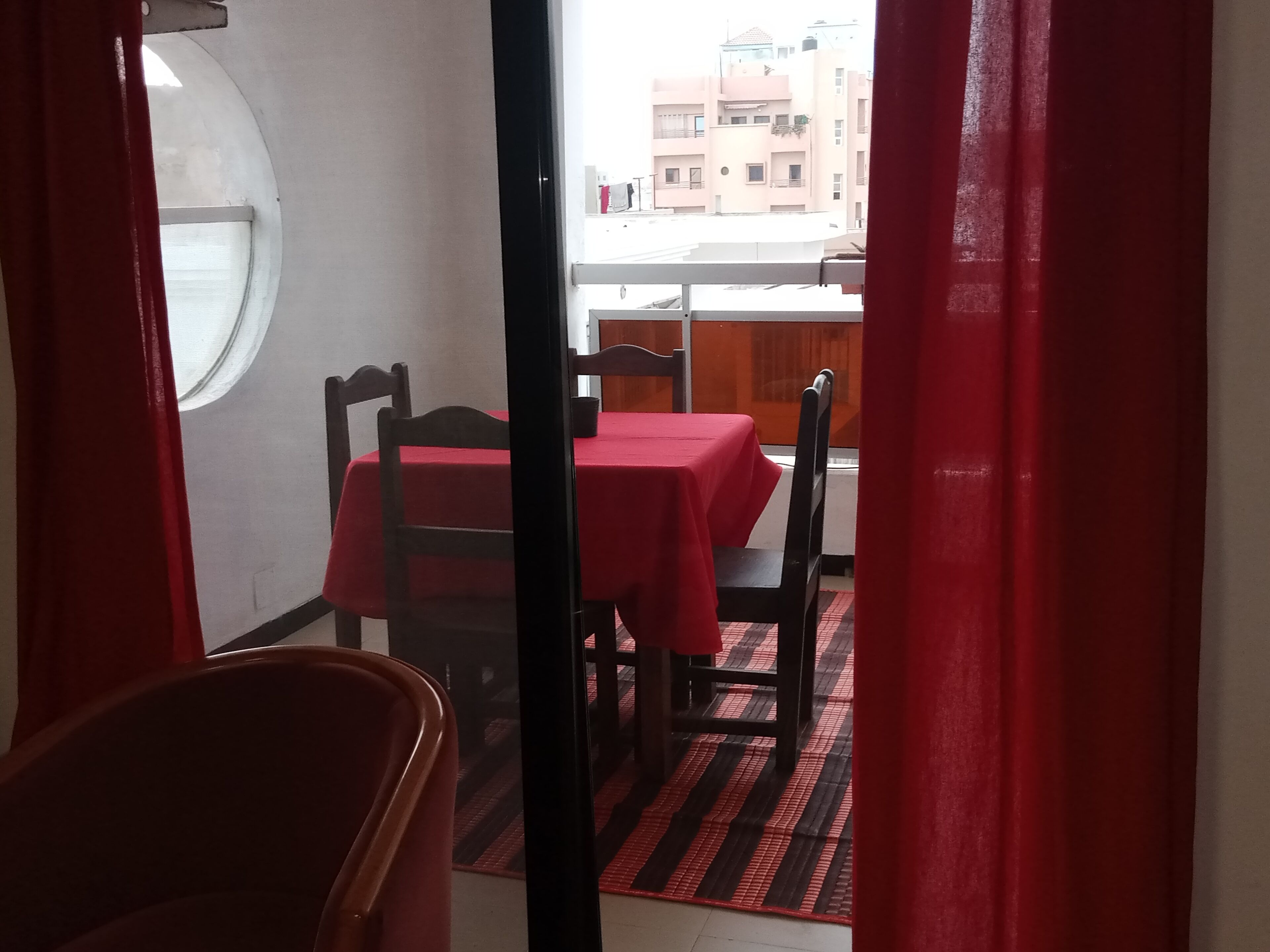 A dining area with a table set for two, a window, and a view of buildings outside.