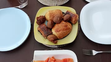 Een tafel met borden eten, waaronder fruit, gebak en een wit bord met blokjes fruit.