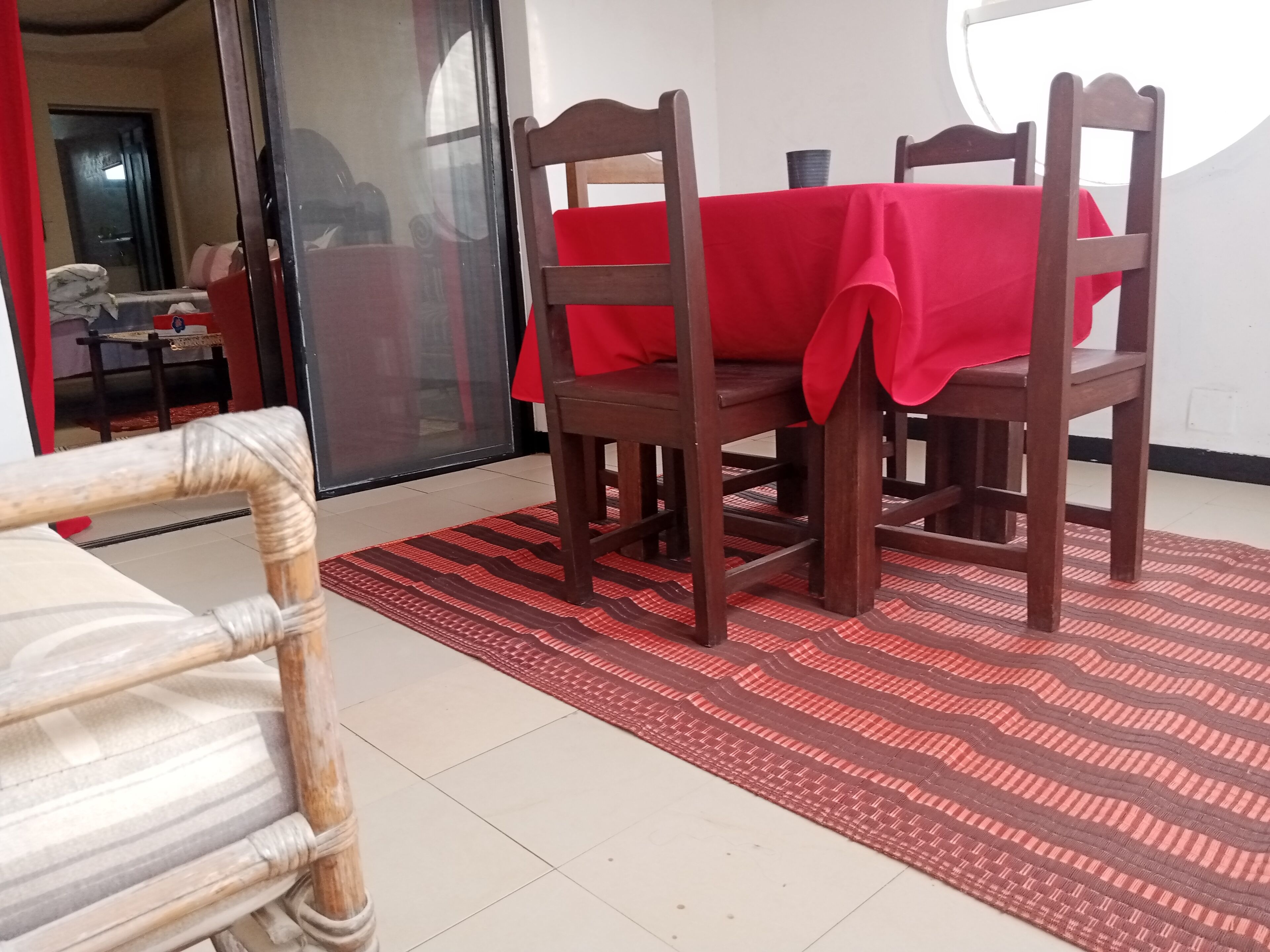Un comedor con mantel rojo, sillas de madera y alfombra estampada.