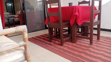 A dining area with a red tablecloth, wooden chairs, and a patterned rug.