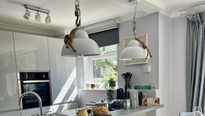 A modern kitchen with a central island, stainless steel appliances, and pendant lighting. - Sunny 2-Bedroom flat in Hoddesdon (Hoddesdon)