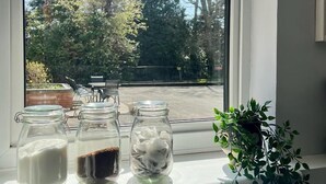 A window with three glass jars containing different items on a white sill. - Sunny 2-Bedroom flat in Hoddesdon (Hoddesdon)