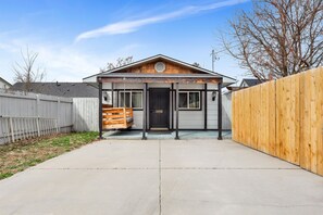 Une maison de plain-pied avec un porche à l’avant, un garage et une clôture en bois.