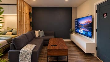 Una sala de estar moderna con un sofá modular, una mesa de centro de madera y un televisor de pantalla plana montado en la pared.