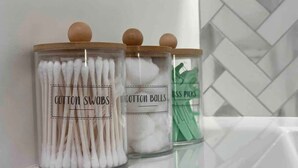 Drei Gläser mit Holzböden, beschriftet mit 'Cotton Swabs', 'Cotton Balls' und 'Lettuce Picks', auf einem weißen Regal.