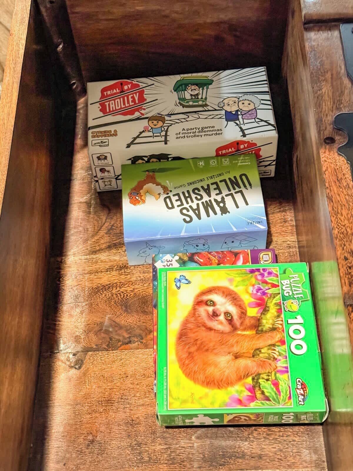 Un tiroir en bois contenant une boîte de casse-tête portant l’inscription « 100 » et une boîte de jeu intitulée « Le défi du chariot ».