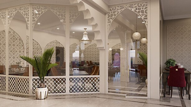 Un interior moderno con elaborados diseños de celosía blanca, una araña y una zona de comedor con una silla roja.