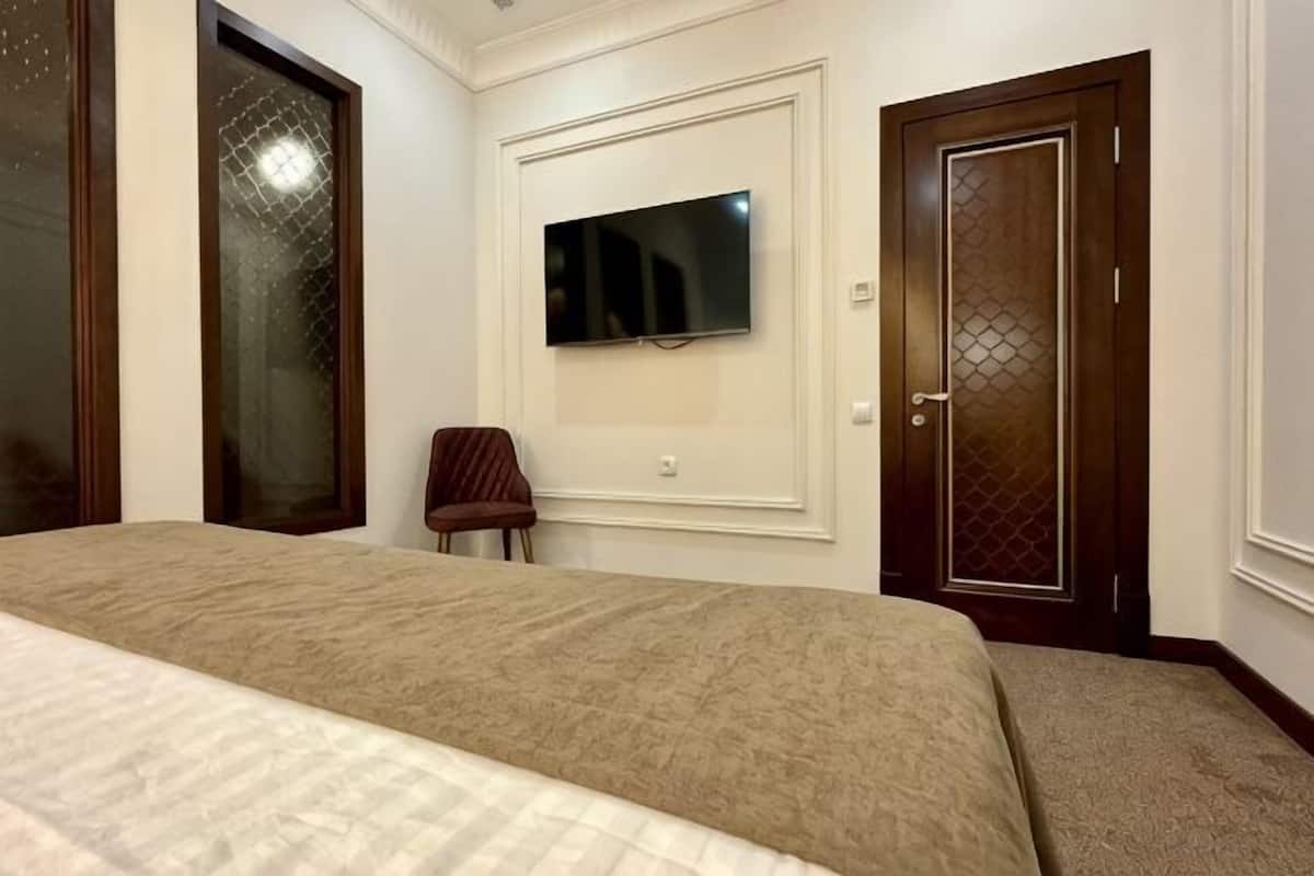 A bedroom with a bed, a TV mounted on the wall, and a door with a decorative panel.