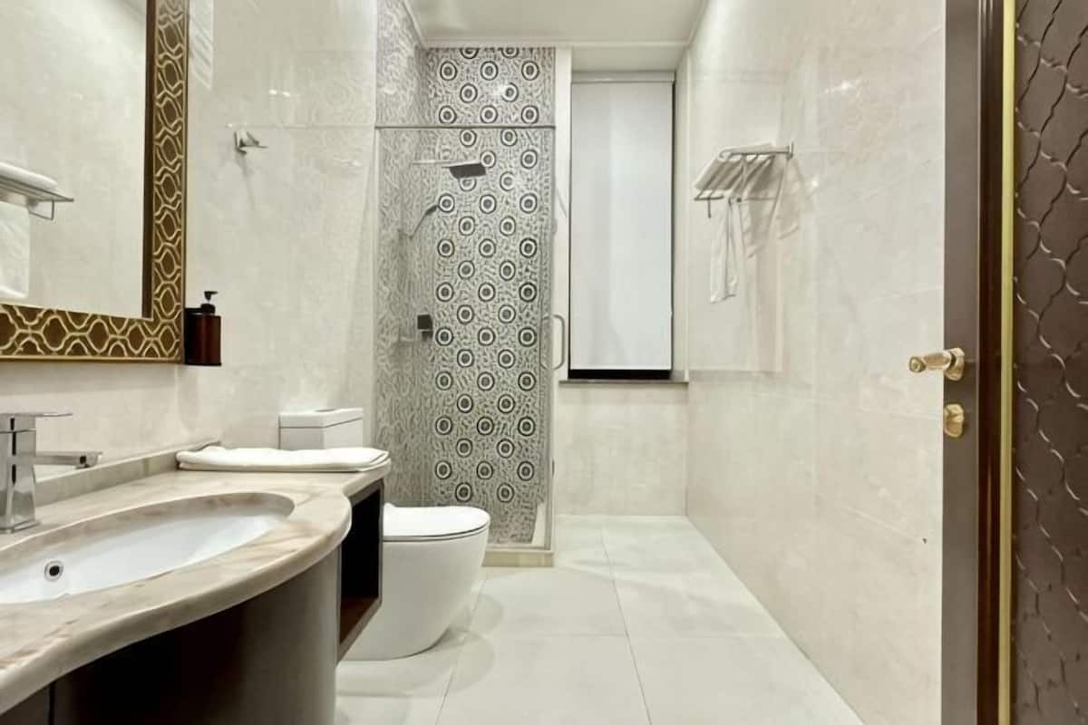 A modern bathroom with a large sink, toilet, and shower area.