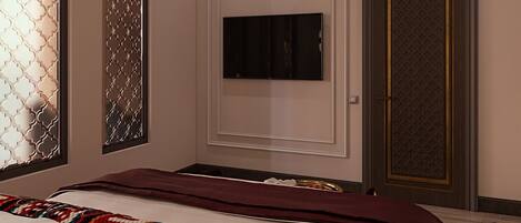 A hotel room with a bed, a TV mounted on the wall, and a door with a patterned design.