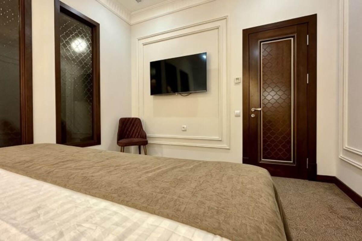 A bedroom with a bed, a TV mounted on the wall, and a door with a decorative panel.