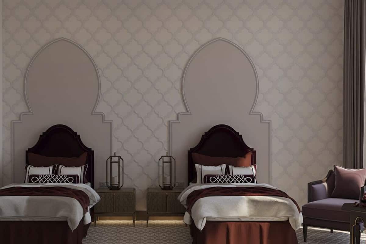 A hotel room with two beds, a nightstand, a chair, and a decorative wall with a geometric pattern.
