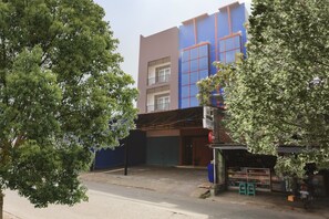 A building with a blue and brown facade, a storefront with a sign, and a tree in the foreground. - Hotel O Citara Jaya Guesthouse (Bekasi)