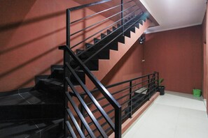 A staircase with black railings and a red wall. - Hotel O Citara Jaya Guesthouse (Bekasi)