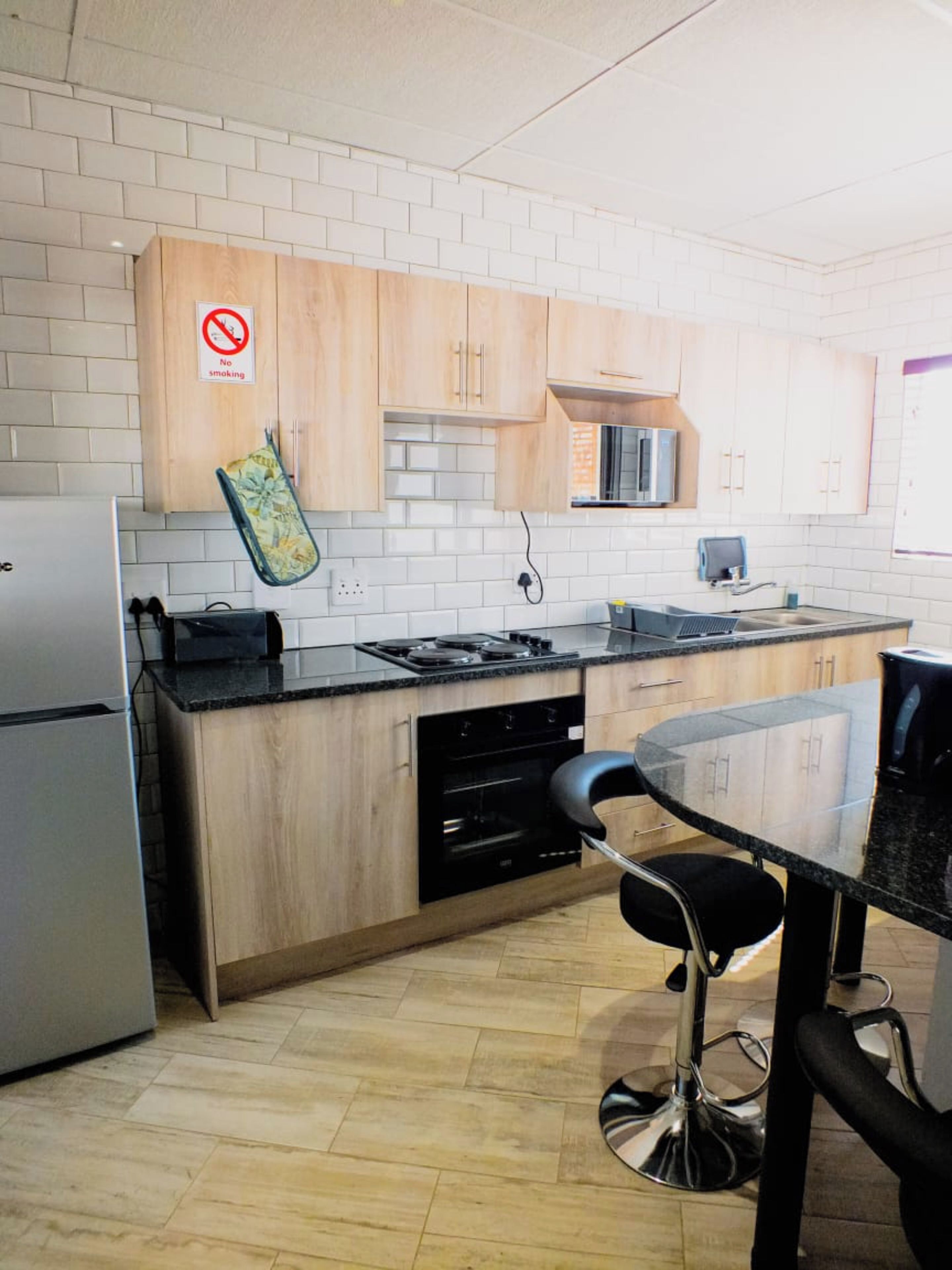 Una cocina moderna con gabinetes de madera, un refrigerador de acero inoxidable, un microondas y una estufa a gas.