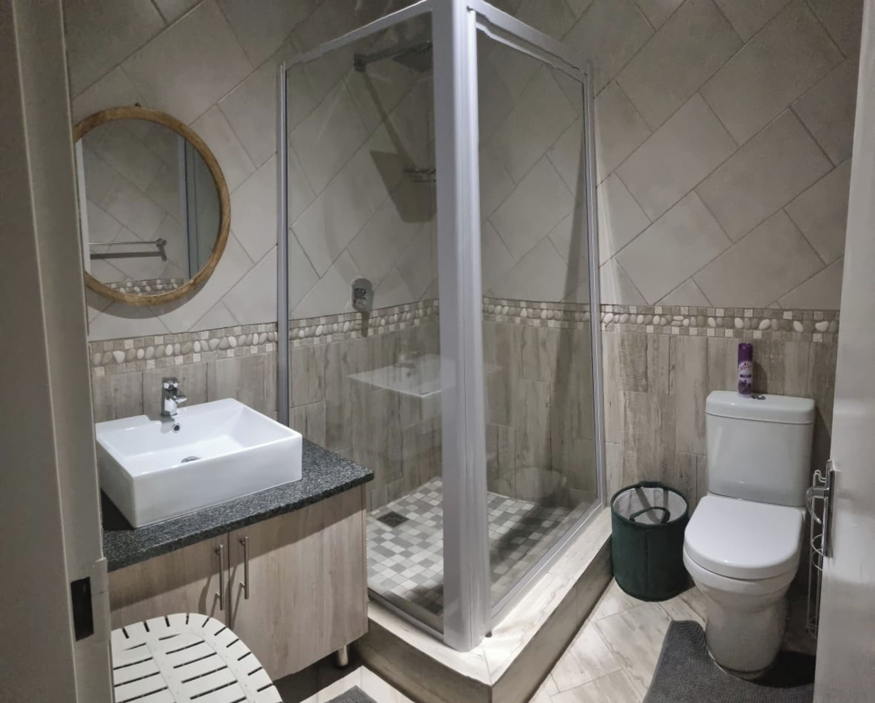Un baño con ducha envuelta en vidrio, lavamanos e inodoro.