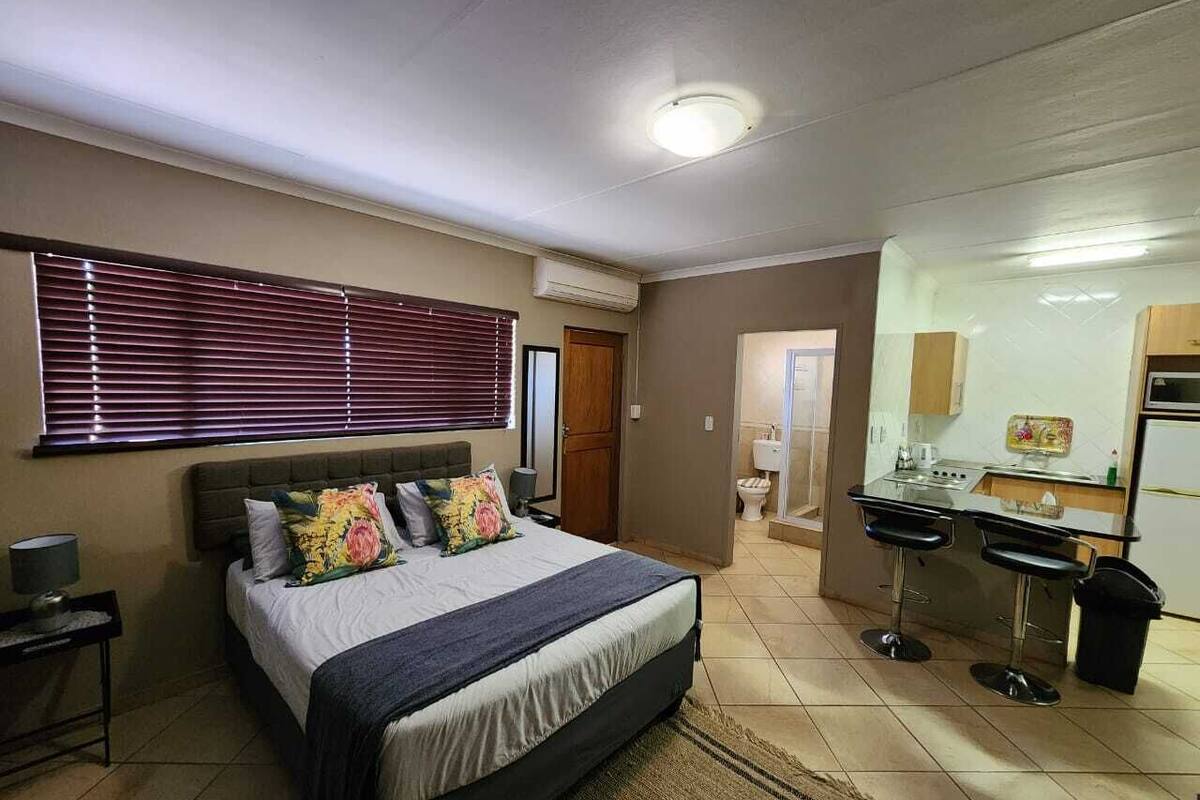 Un dormitorio con cama, mesita de noche y un pequeño escritorio con silla.