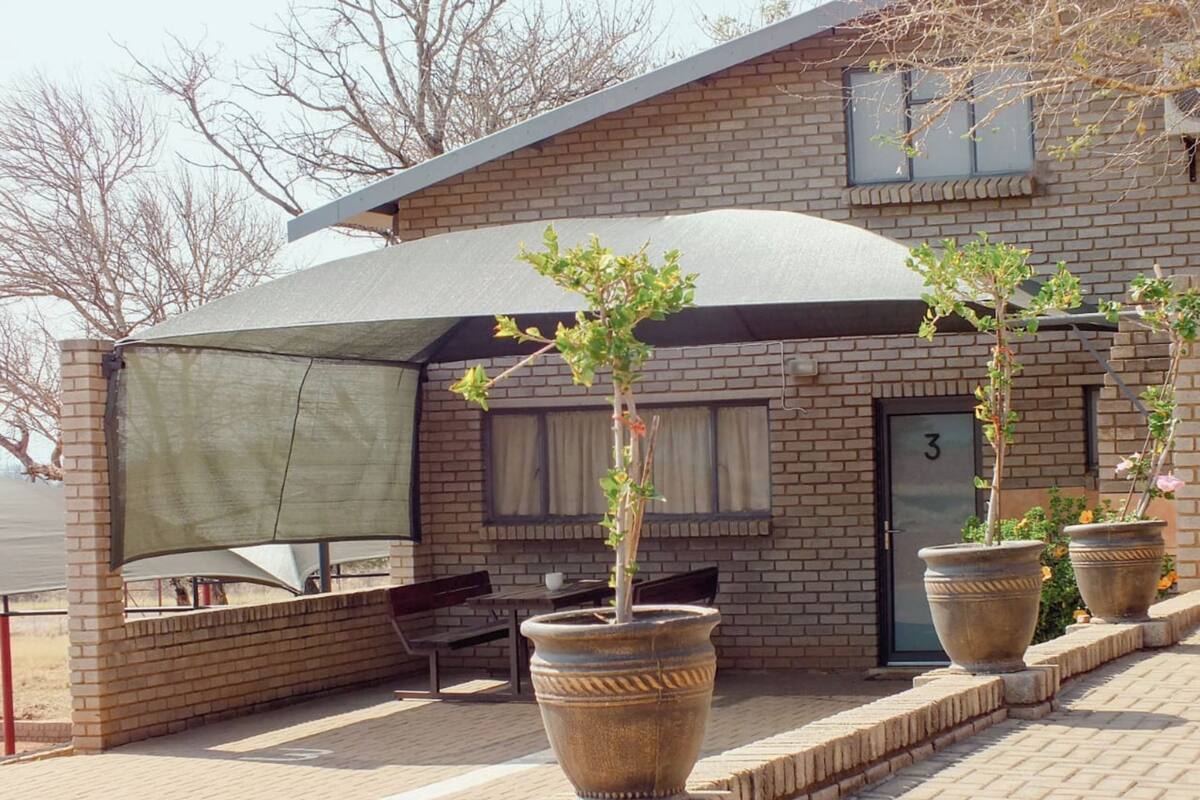 Un edificio de ladrillo con un patio cubierto, mobiliario exterior y plantas en macetas.