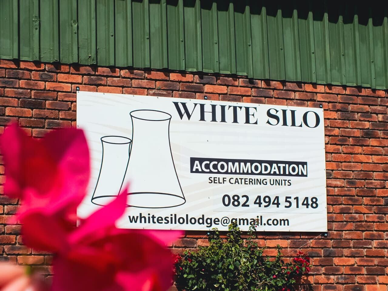 Señal de White Silo Accommodation con unidades de cocina propia, número de contacto y dirección de correo electrónico.