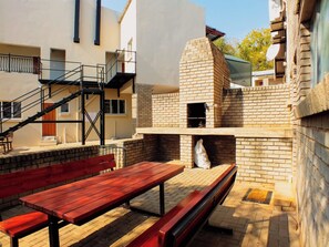 An outdoor patio with a brick oven, wooden benches, and a staircase leading to an upper level. - White Silo Accommodation (Thabazimbi)