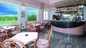 A restaurant with outdoor seating, a bar, and a view of a green landscape. - hotel CASABLANCA (Lazise)