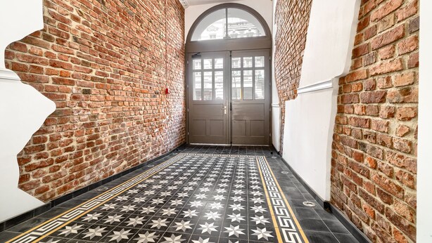 A narrow hallway with brick walls and a tiled floor. - MARGI Daphne Apartment (Szczecin)