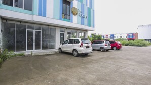 A building with a sign reading "The Rega" and a parking lot with several cars. - Collection O Bekasi Timur Near Gedung Juang Formerly Regia Tambun (Cikarang)