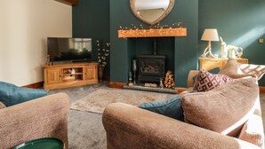Ein gemütliches Wohnzimmer mit Kamin, Fernseher und bequemen Sitzgelegenheiten.