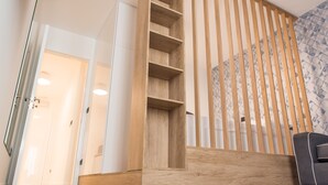 A wooden staircase with open shelves, a grey sofa, and a patterned wall. - Deluxe, Charming and Cozy Bcadria Apartment A2 (Split)