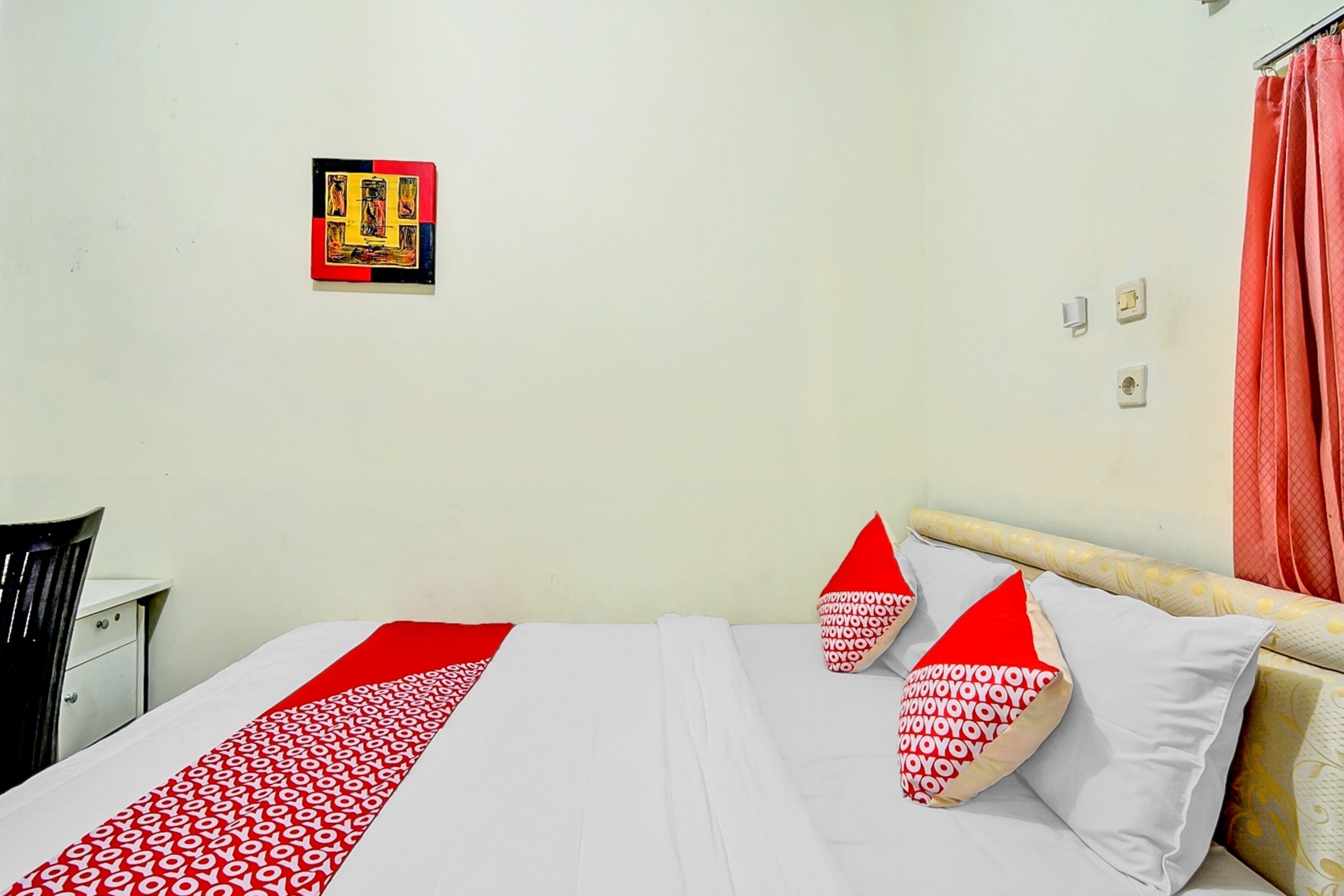 Una camera d'albergo con un letto, una scrivania e un'opera d'arte appesa al muro.