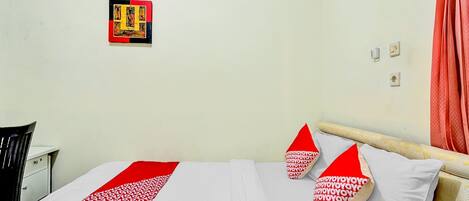 A hotel room with a bed, a desk, and a wall-mounted artwork.