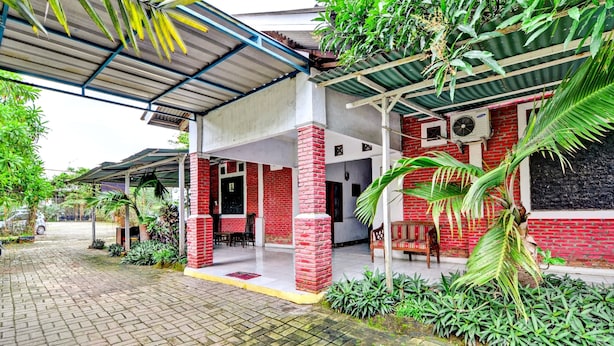 A covered outdoor area with a brick building, a covered seating area, and a paved walkway. - OYO 90222 Lafa Park Syariah (Cikarang)
