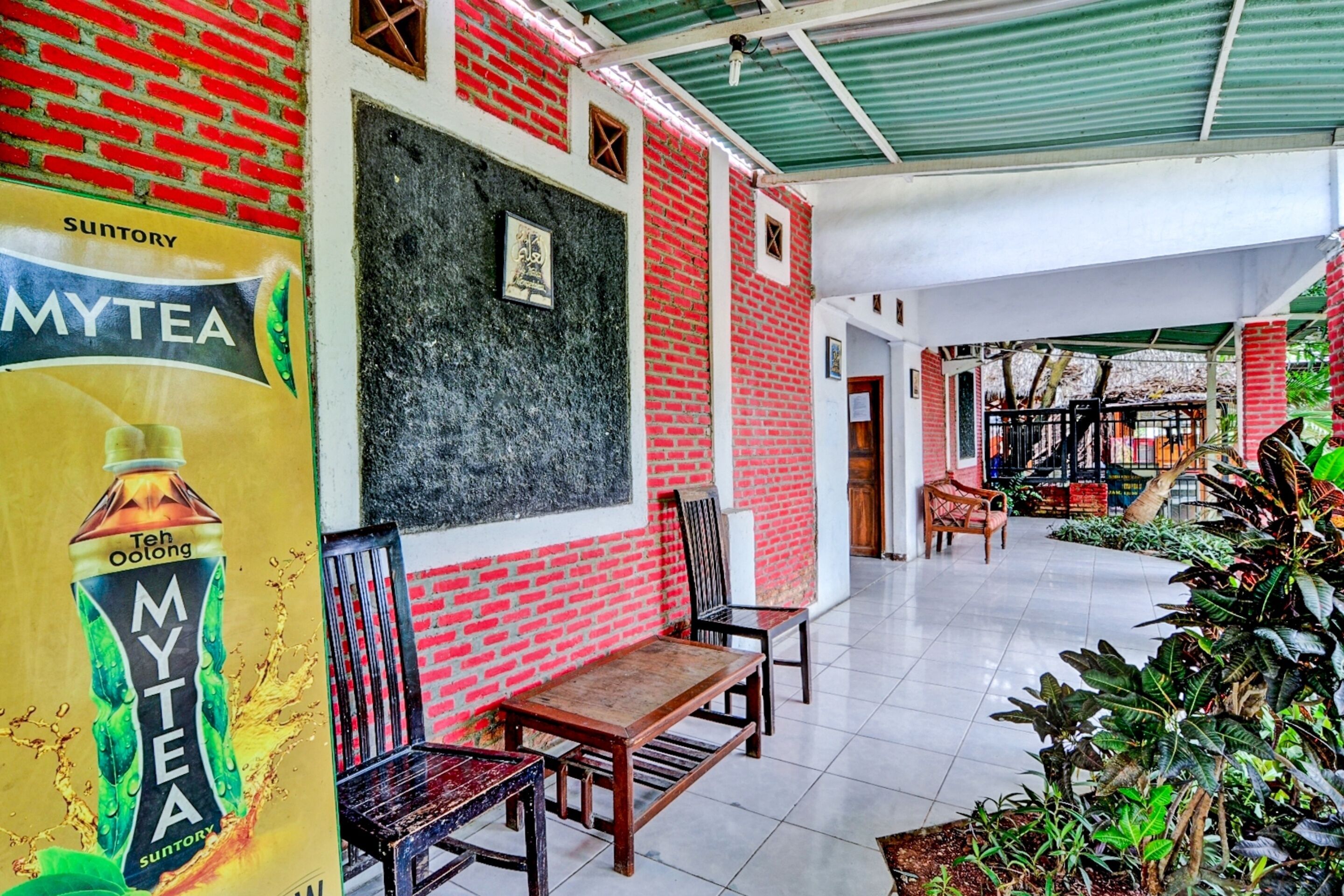 A spacious indoor area with red brick walls, wooden furniture, and a variety of plants.