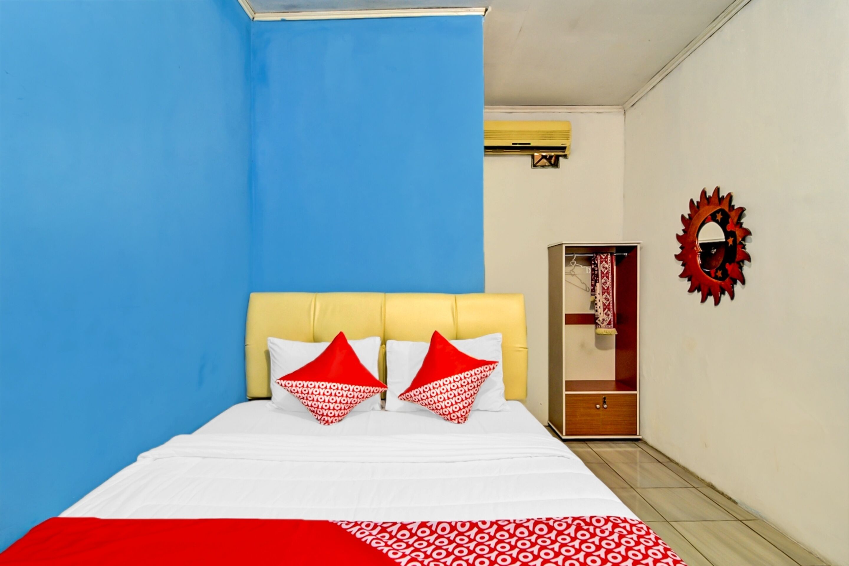 A bedroom with a bed, a wardrobe, and a mirror on the wall.