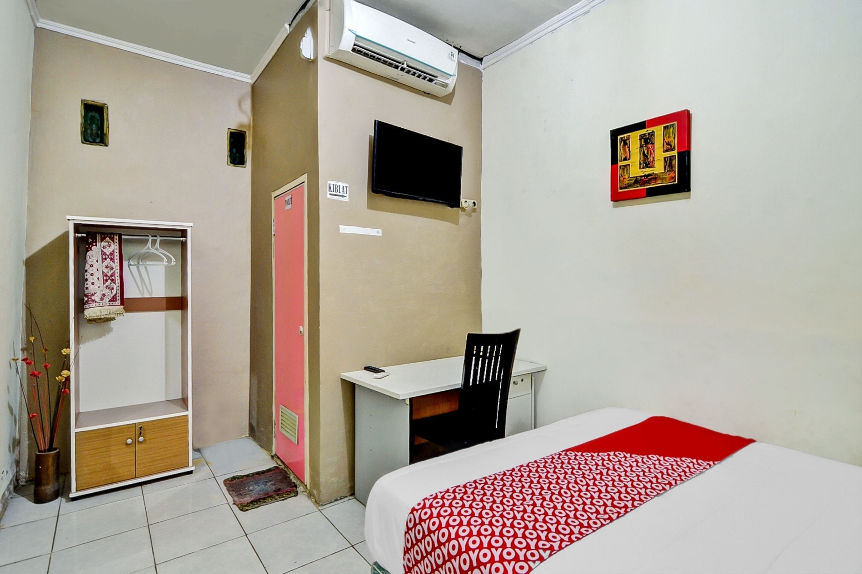 Een slaapkamer met een bed, bureau, stoel, kledingkast en televisie.