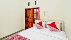 A bedroom with a bed, a wooden door, and a window with curtains. - OYO 90222 Lafa Park Syariah (Cikarang)