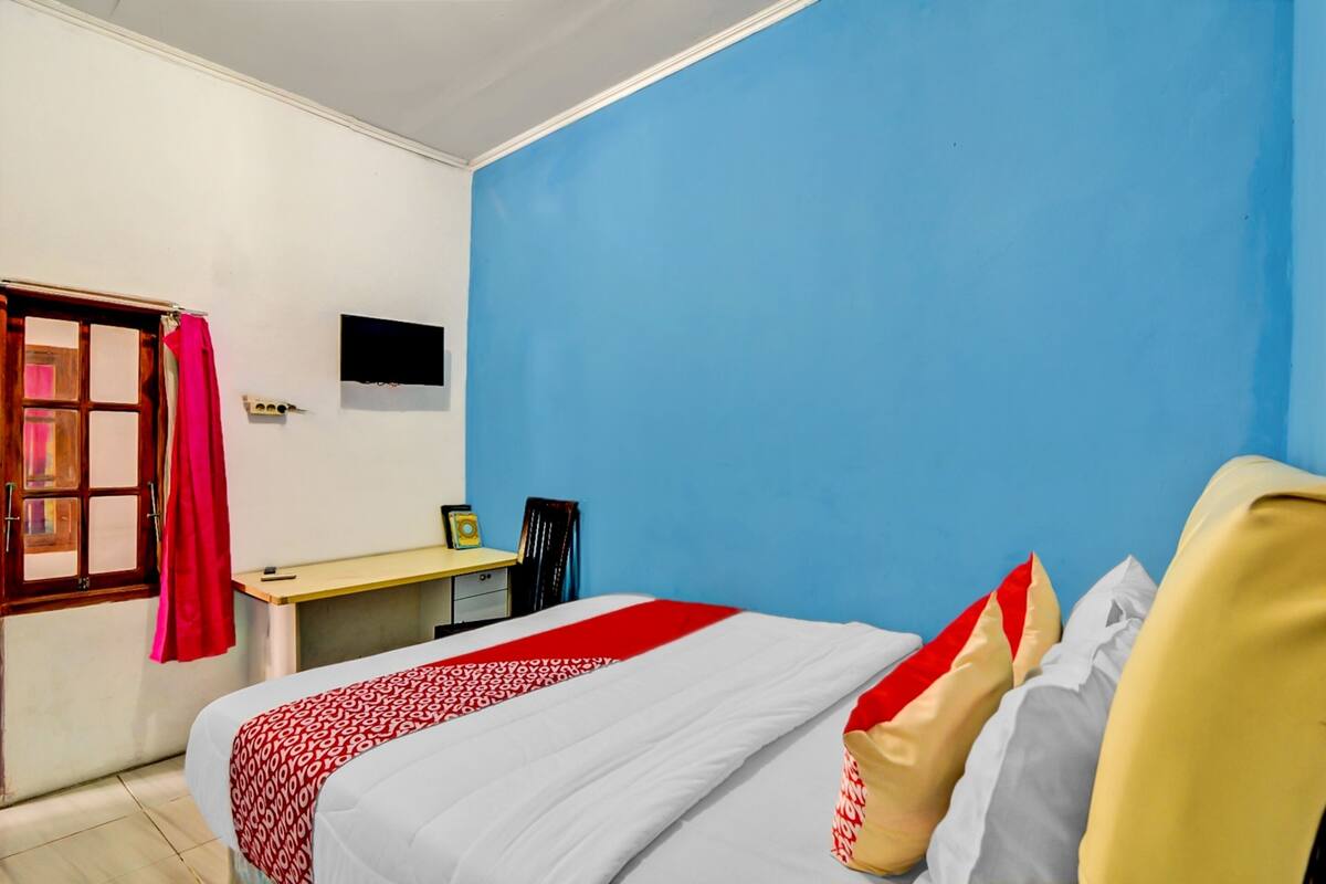 Een hotelkamer met een bed, een bureau en een televisie aan de muur.